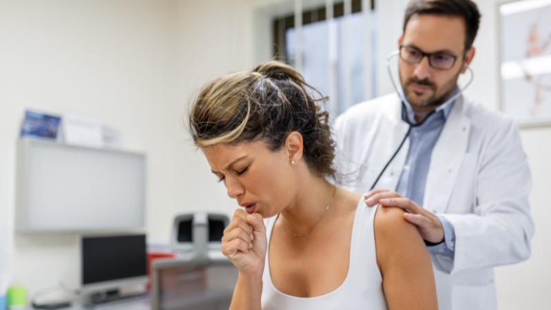 Lekar sluša pluća pacijentkinje koja kašlje tokom pregleda u ordinaciji