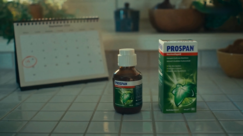 Bočica i kutija Prospan sirupa stoje na kuhinjskom pultu pored kalendara u pozadini