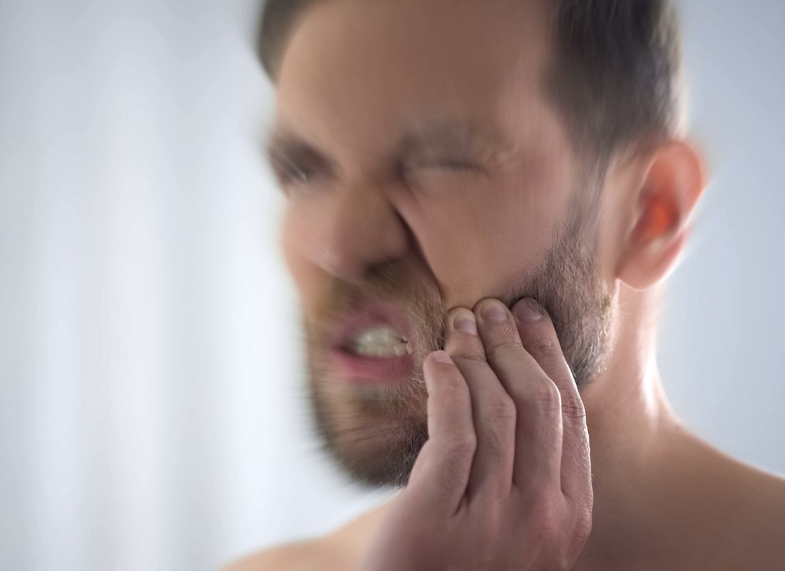 momak koji pati od napetosti mišića u vilici se drži za lice od bola