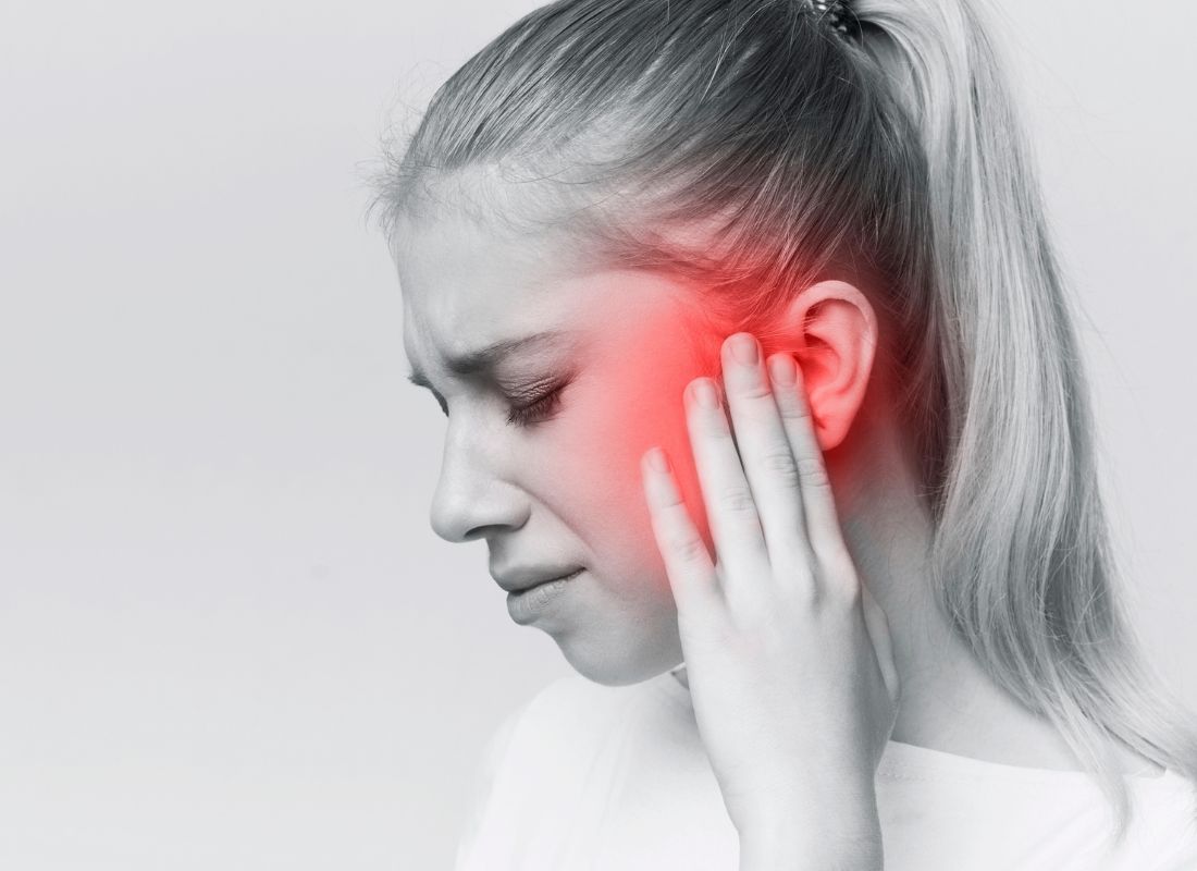 devojka se drži za uvo od bola